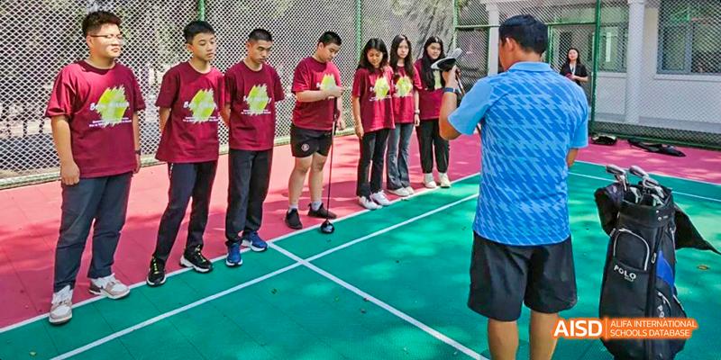 Students from Beilu Academy, standing in a line with their feet on a white line on a field.