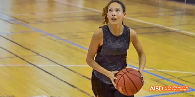 A female student from Beilu Academy, dribbling a basketball on a court during a game.