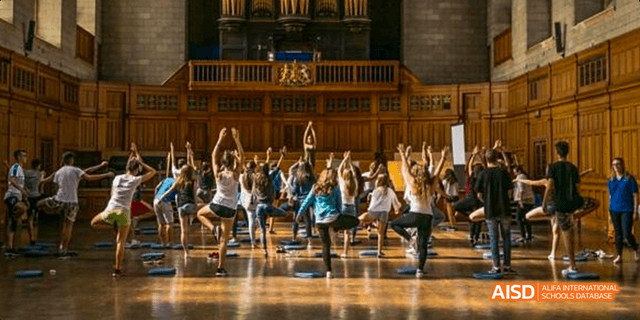 A large group of students from Beilu Academy, sitting and stretching on the floor of a gym.