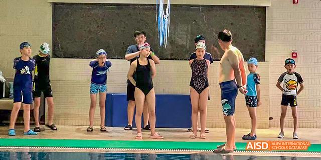 A group of students from Beilu Academy, standing by the edge of a swimming pool with an instructor.