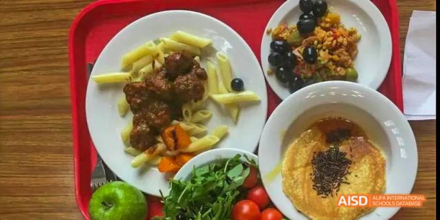 A plate with pasta and meatballs, along with a side salad, representing a meal served at Beilu Academy.