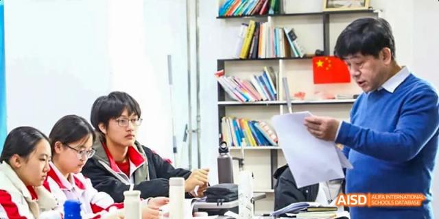 Camford Royal School student receiving a paper during a classroom activity with bookshelves in the background.