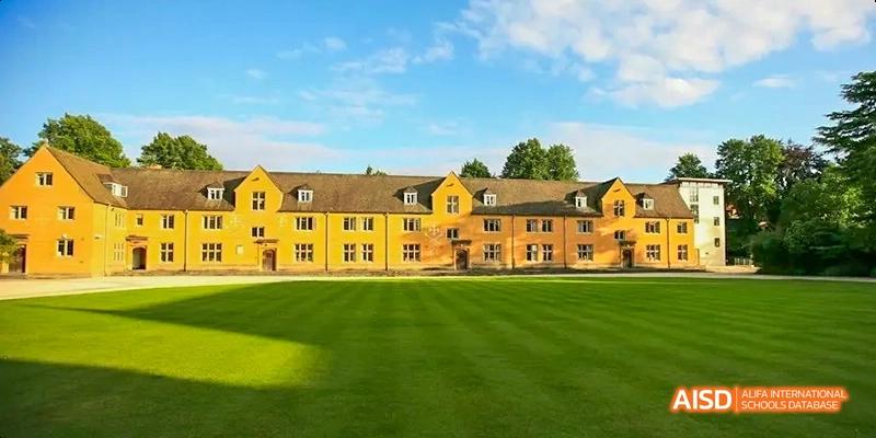 Camford Royal School campus building with wide green lawn under blue sky