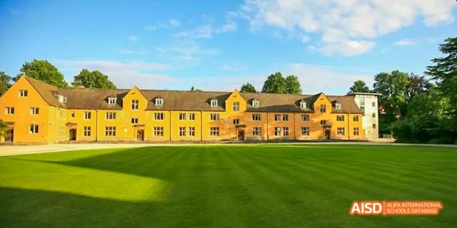 Camford Royal School campus building with wide green lawn under blue sky