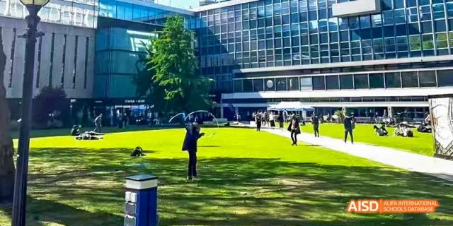 Camford Royal School campus with students gathered on a green lawn near modern buildings