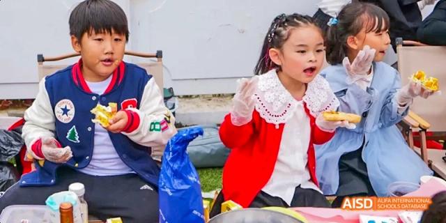 Camford Royal School young students enjoying snacks while sitting outdoors.