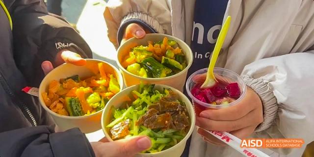 Camford Royal School students holding bowls of colorful, healthy meals.