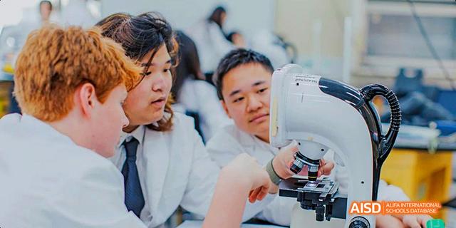 A student from the Canadian International School of Guangzhou is focused on a task while a teacher looks over their shoulder.