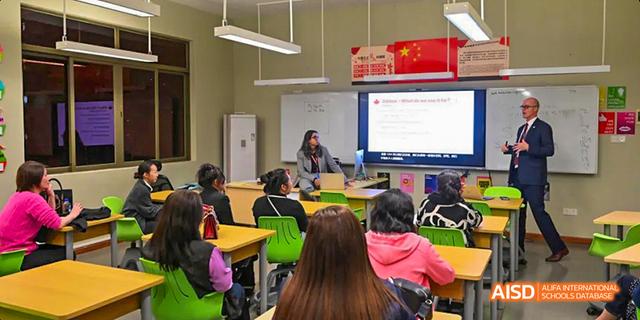 A teacher from the Canadian International School of Guangzhou is seen instructing a group of students in a classroom.