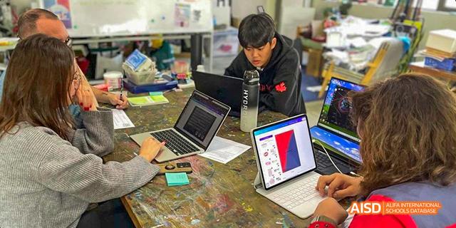 An open laptop is placed on a colorful, painted desk at the Canadian International School of Guangzhou.