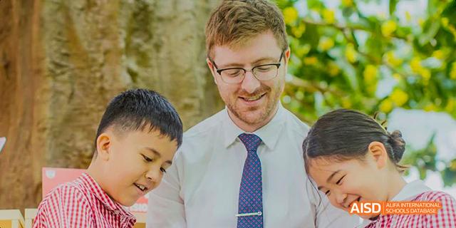 A male teacher from the Canadian International School of Guangzhou smiles at students.
