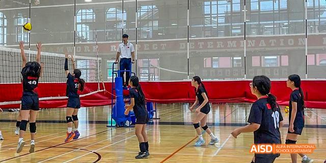 A volleyball match is in progress with two students from the Canadian International School of Guangzhou on one side of the net, while the referee stands on an elevated platform.