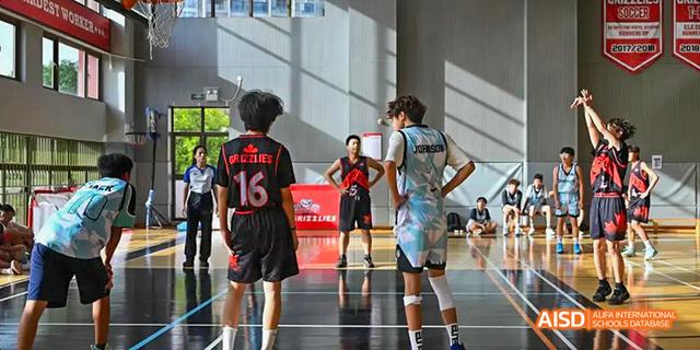 Two students from the Canadian International School of Guangzhou are playing basketball on the indoor court.