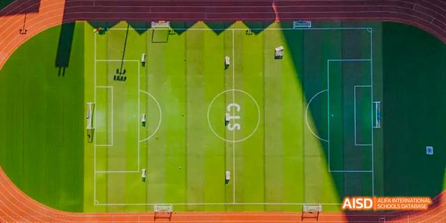 An aerial view of a soccer field at the Canadian International School of Guangzhou, with the letters "CIS" visible on the grass.