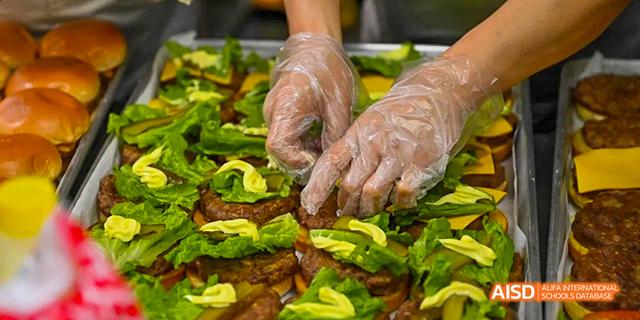 A staff member from the Canadian International School of Guangzhou is seen preparing burgers with fresh avocados.
