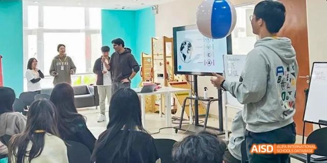 Students and teachers at Dalian American International School watching a presentation on a screen.