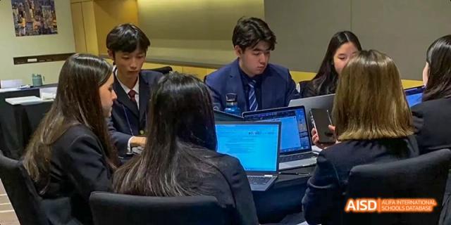 Two students at Dalian American International School working together on a laptop.