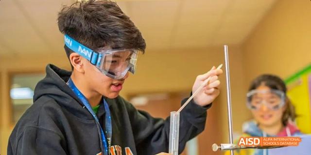 A young person at Dalian American International School wearing safety goggles and gloves.