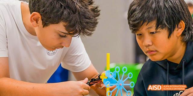 Two students at Dalian American International School building something together.