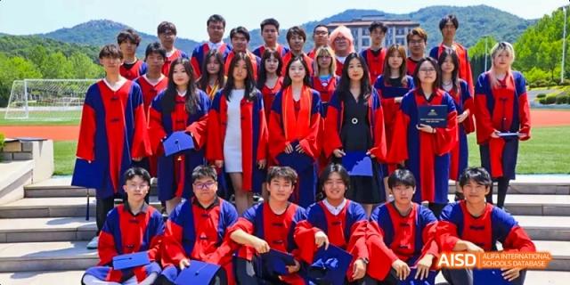 A group of students at Dalian American International School wearing matching red outfits and smiling for a photo.