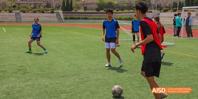 A male student from Dalian American International School is playing soccer on a field.