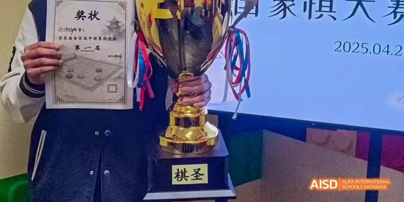 A person is holding a gold trophy with ribbons, at an event for Dalian American International School.