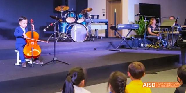 The back of a drum kit on a stage with an audience watching at Dalian American International School.