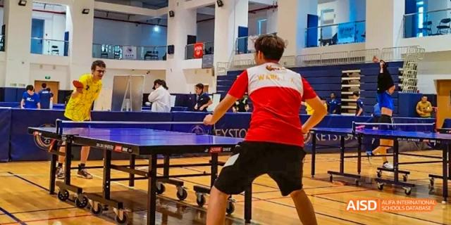 Two people playing a game of ping-pong at Dalian American International School.
