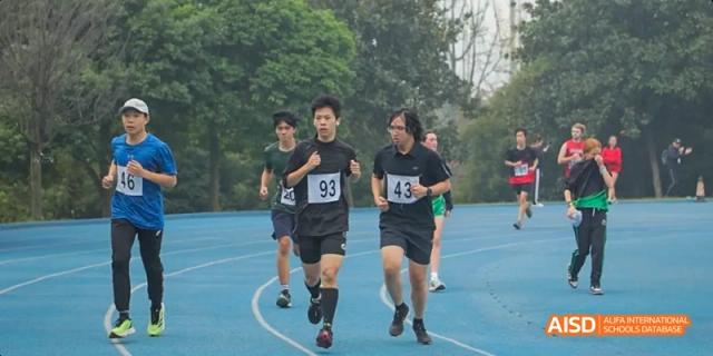 Two students running a race on a blue track at Dalian American International School.