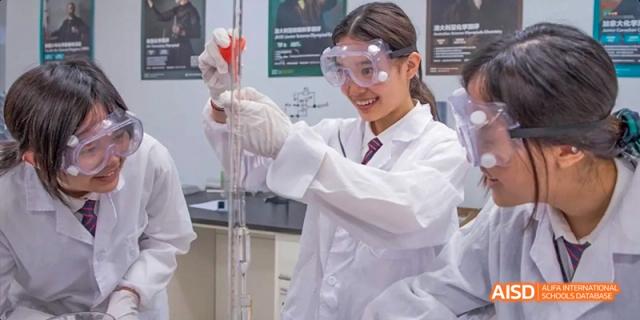 A female student in a lab coat and goggles in a science class at Dipont KCS Chengdu.