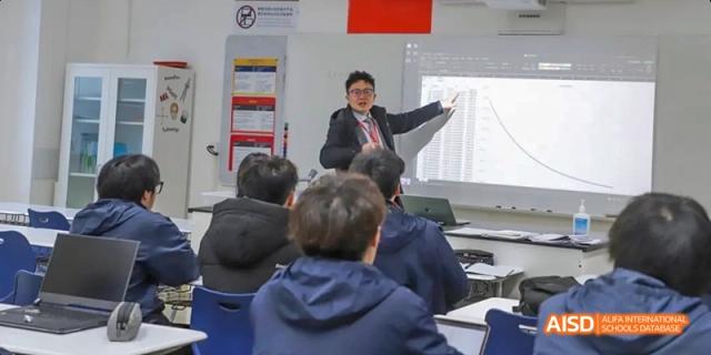 A teacher pointing to a presentation board while students watch at Dipont KCS Chengdu.