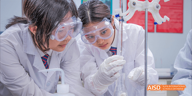 A female student in a lab coat and safety goggles in a science class at Dipont KCS Chengdu.