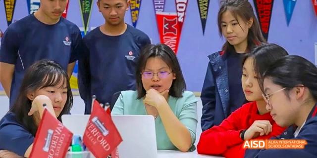 A female student in glasses sitting in front of a laptop at Dipont KCS Chengdu.