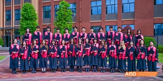 A group of students in graduation caps and gowns posing for a photo at Dipont KCS Chengdu.