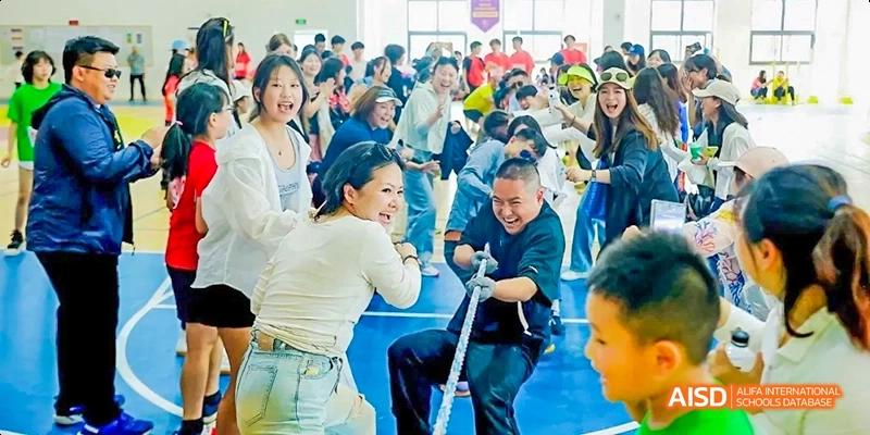 Dipont KCS Chengdu students and staff participate in a tug-of-war competition at a school event.