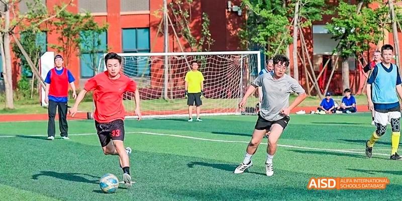 Dipont KCS Chengdu students play a game of soccer on a green field.