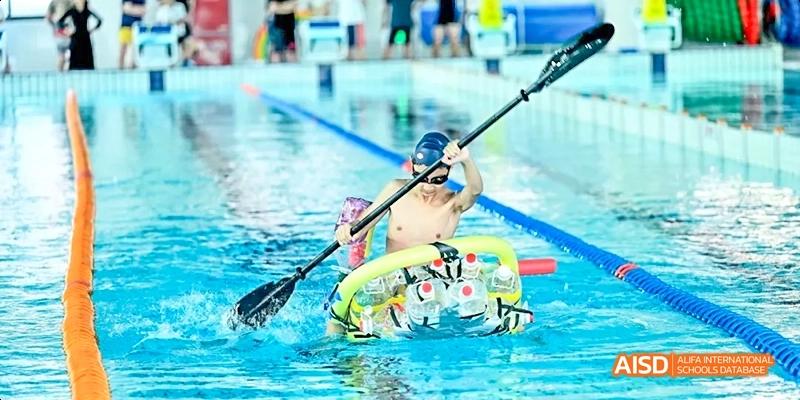 A Dipont KCS Chengdu student in a kayak paddles across a swimming pool.