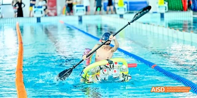 A Dipont KCS Chengdu student in a kayak paddles across a swimming pool.