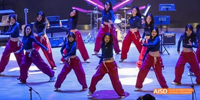 Dipont KCS Chengdu students perform a choreographed dance on a stage.