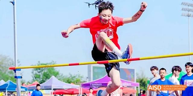 A Dipont KCS Chengdu student participates in a high jump competition, clearing the bar with a scissor kick.