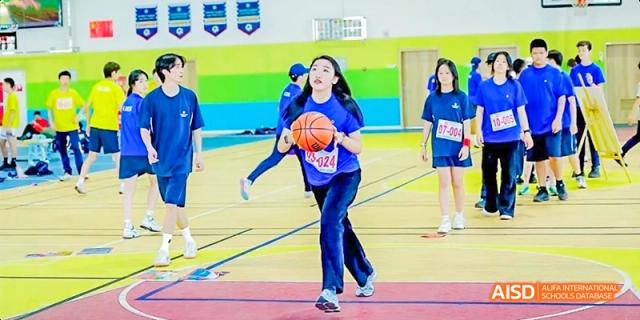 A Dipont KCS Chengdu student runs while dribbling a basketball across a gymnasium floor.