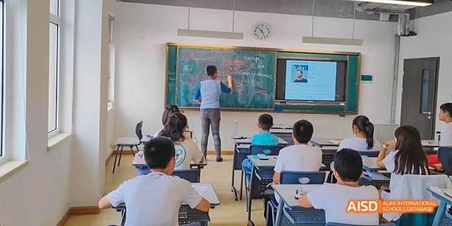 Ealing International School students are in a classroom, with one student at the blackboard and others seated at their desks.