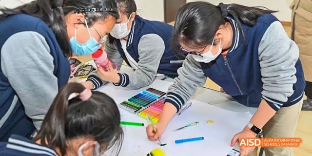 Ealing International School students are working together on a craft or art project at a table.
