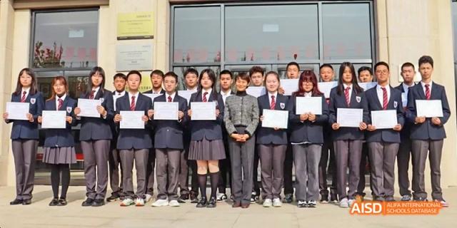 A group of Ealing International School students in uniform posing for a photo outside.