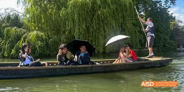 Ealing International School students are punting in a boat on a river, with green trees hanging over the water.