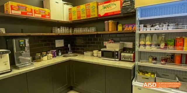 An empty, modern Ealing International School kitchen with dark cabinets and a microwave.
