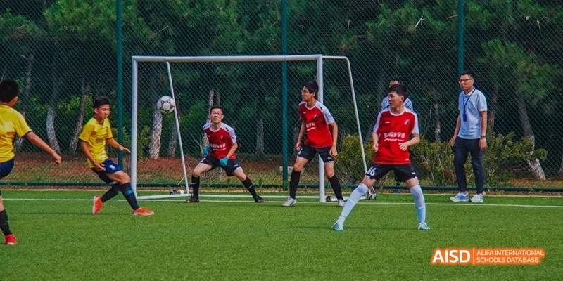Ealing International School students playing soccer on a green field.