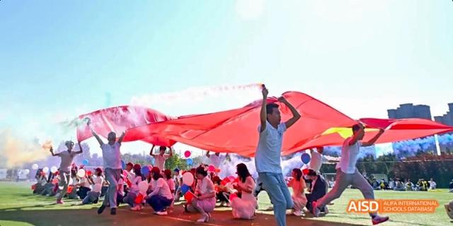 Ealing International School students holding a large red banner at an outdoor event.