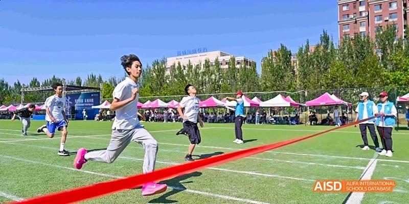 Ealing International School students participating in a tug-of--war event on a sports field.