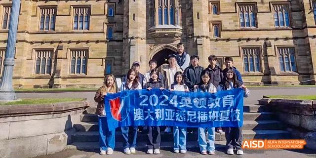 Ealing International School students holding a banner in front of an old stone building.